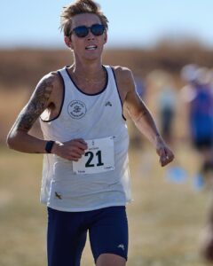 Charlie Lawrence runs with a blurred field background wearing running bib number 21