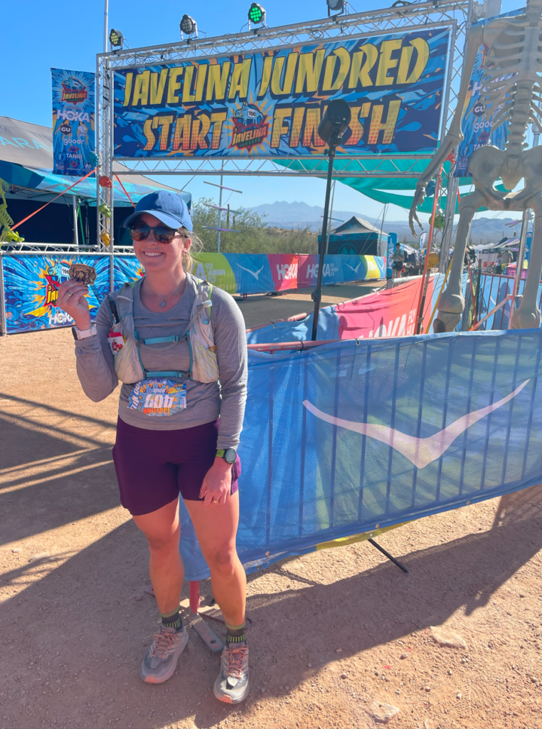 Coach Holly Martin at the finish line of the Javelina Jundred holding a medal