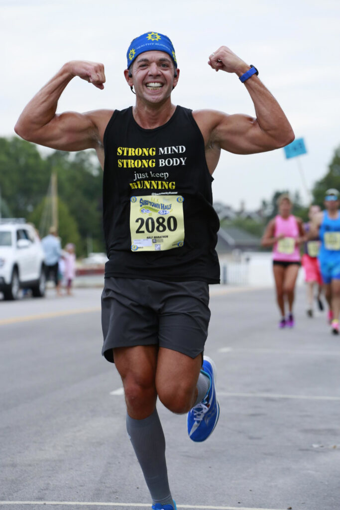 Achilles expert Duane Scotti running with his arms in a muscle pose